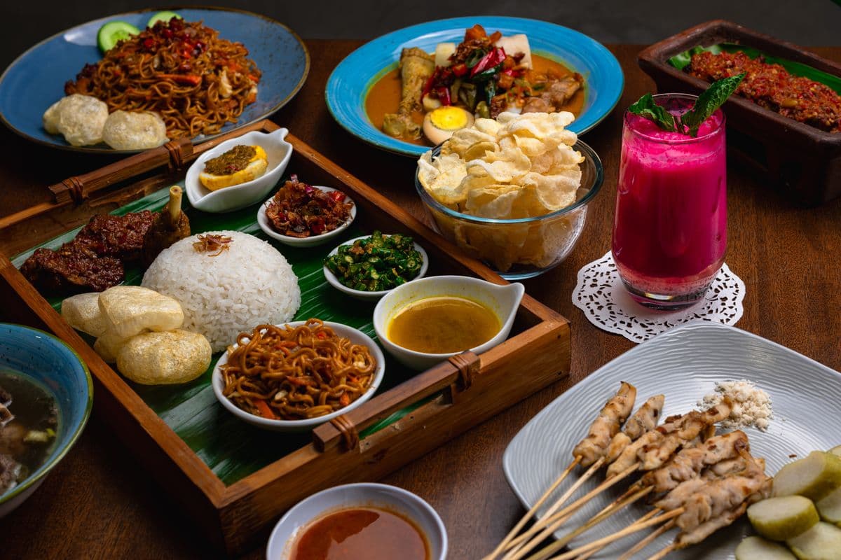 Ilustrasi sate ayam dan hidangan Indonesia di meja