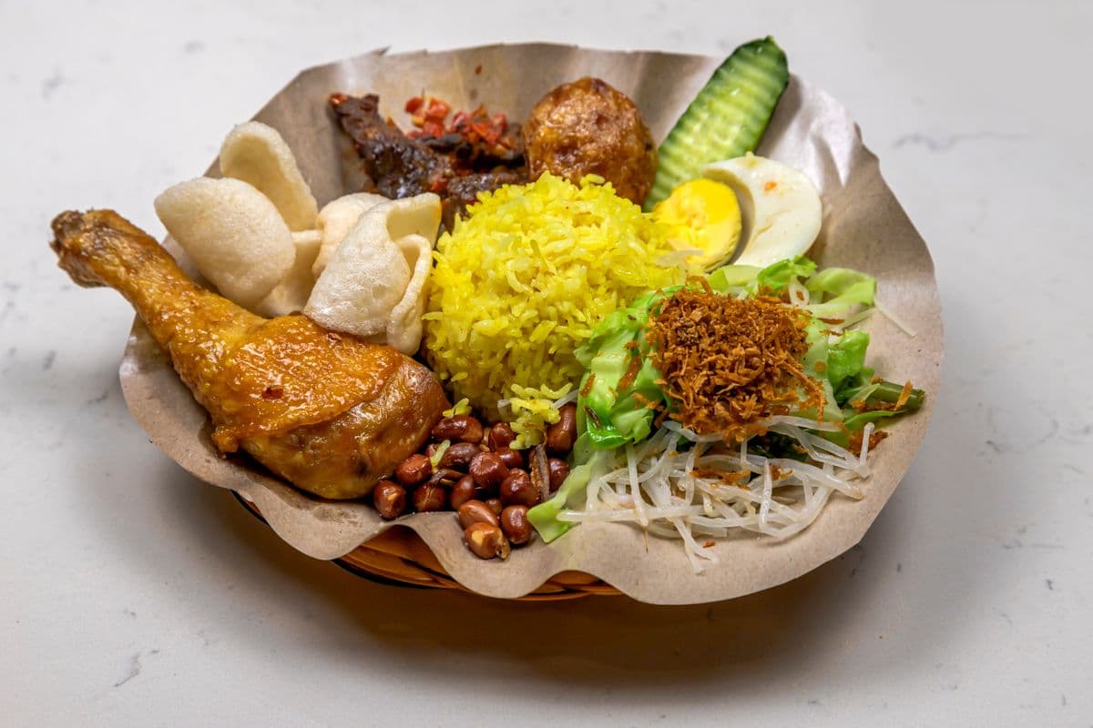 Ilustrasi nasi kuning dengan ayam, telur, dan lauk pendamping